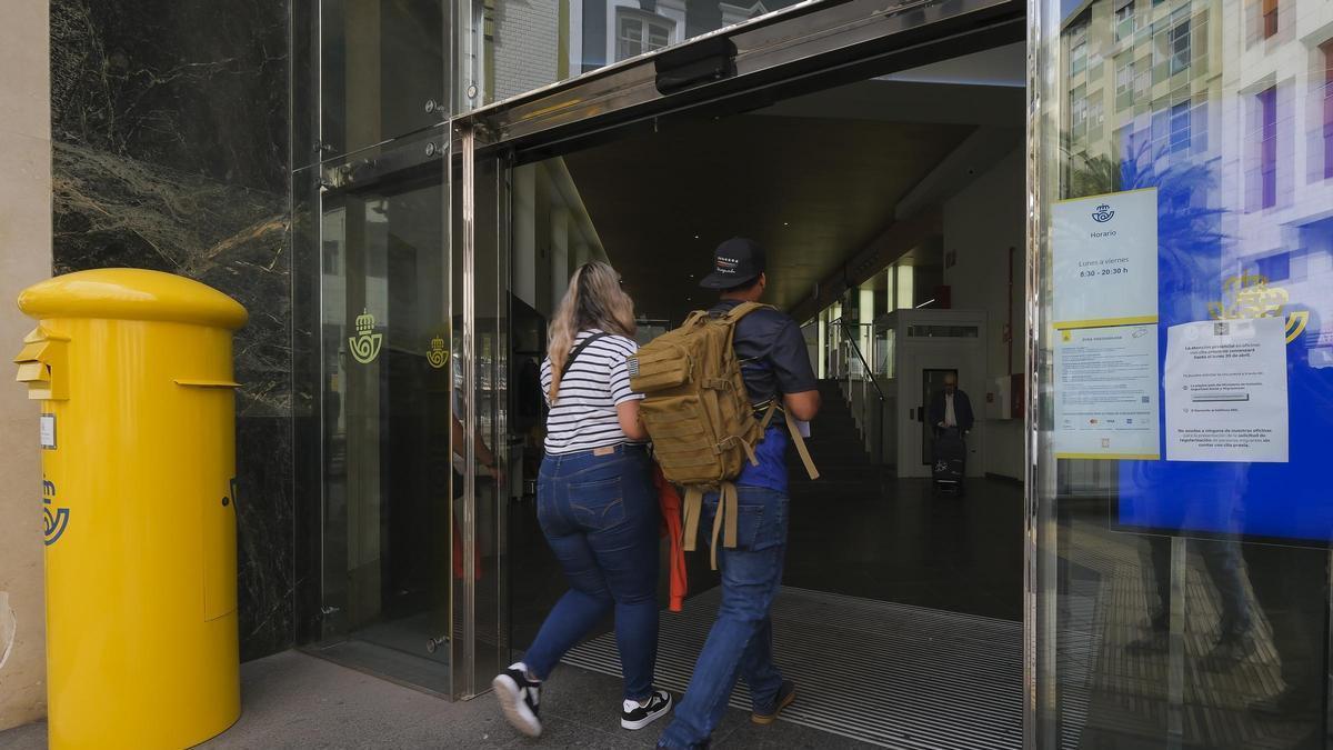 Dos personas migrantes entran en una oficina de Correos de la capital grancanaria para realizar el trámite de regularización.