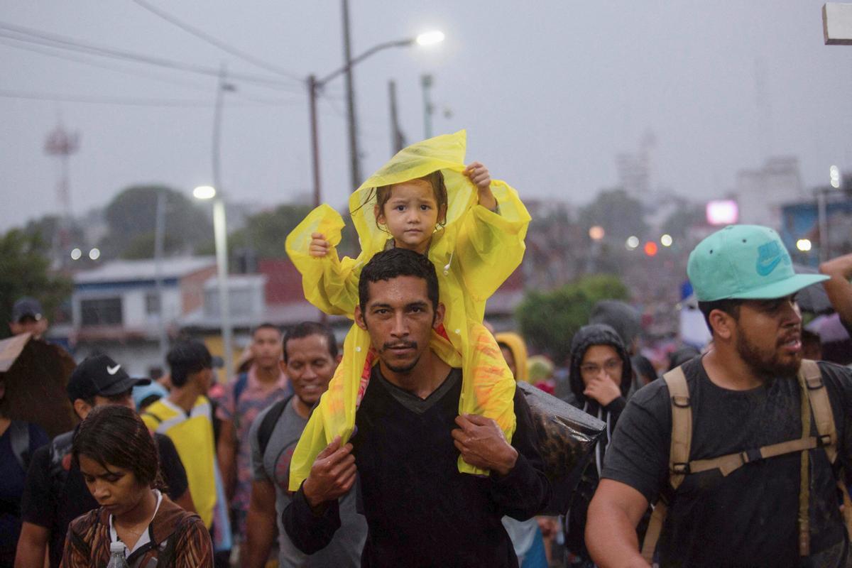 Un niño se sienta sobre los hombros de un hombre, mientras los migrantes forman parte de una caravana que cruza el país para llegar a la frontera de los EE. UU., mientras los líderes regionales se reúnen en Los Ángeles para discutir la migración y otros temas.