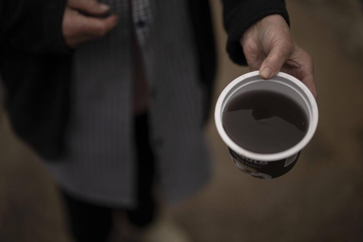Una vecina de Valdegodos, en Vilamartín, muestra el color y estado del agua de la red pública.