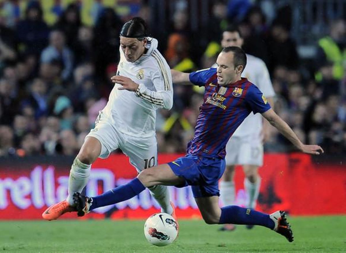 Andres Iniesta es disputa una pilota amb Özil durant la primera part del partit.