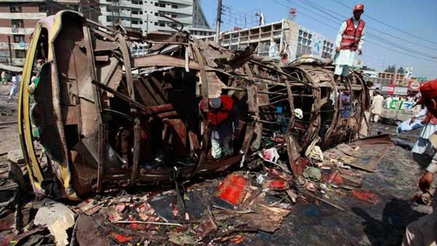 Varios operarios revisan el autobús que destrozaba una bomba esta mañana.