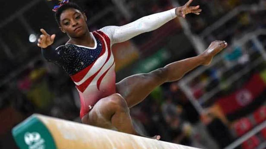 Biles, concentrada, durante un ejercicio en la barra de equilibrio.