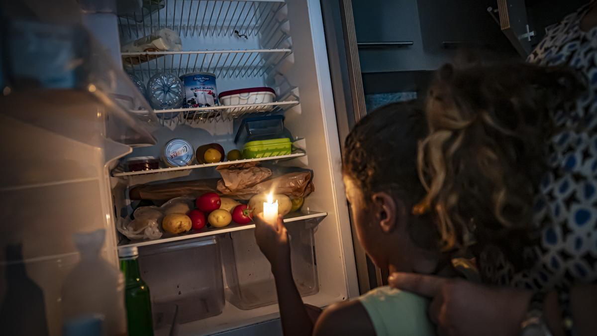 La hija de Fouzia abriendo la nevera vacía con una vela