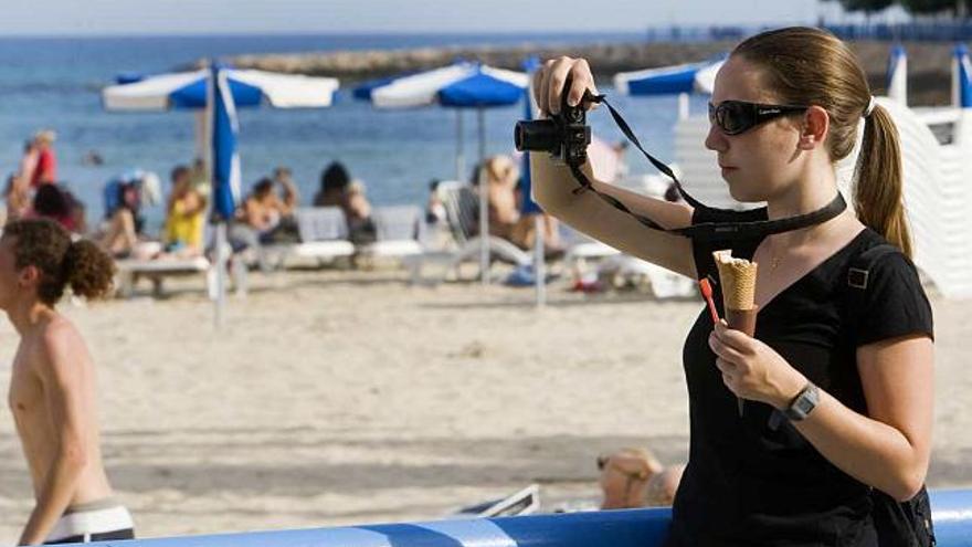 Una joven saca fotos mientra se come un helado, ayer en la playa del Postiguet.