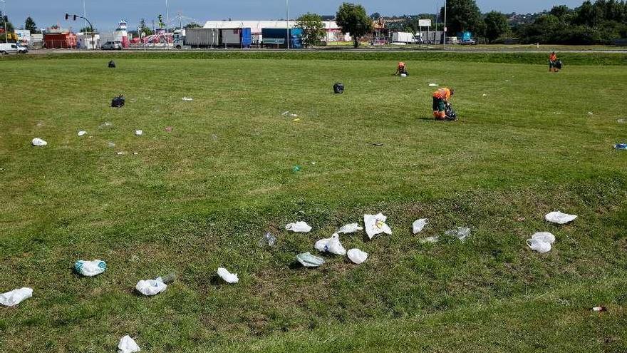 Operarios de Emulsa, recogiendo, ayer por la mañana, los restos del &quot;macrobotellón&quot; en Cabueñes.