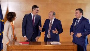 El presidente del Gobierno, Pedro Sánchez, conversa con el presidente del PNV, Andoni Ortuzar, en presencia de la vicepresidenta primera, María Jesús Montero, y el portavoz parlamentario Aitor Esteban, tras firmar el acuerdo de investidura.
