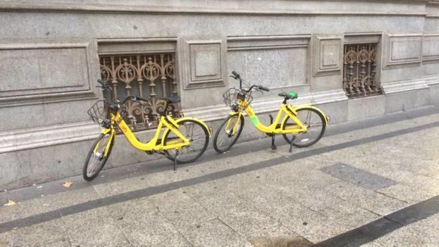 Dos bicis de alquiler compartido aparcadas en la acera de la Gran Vía de Madrid.