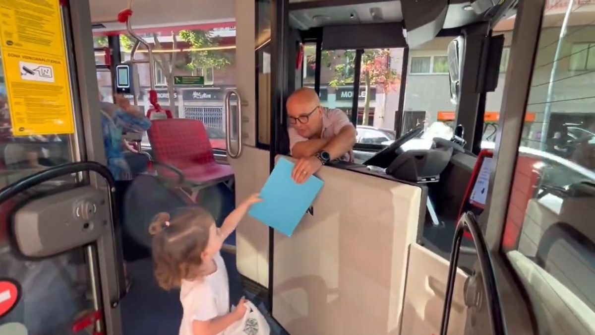 Roque López, conductor de TMB, reparte unas láminas para colorear a una niña al subir al bus.