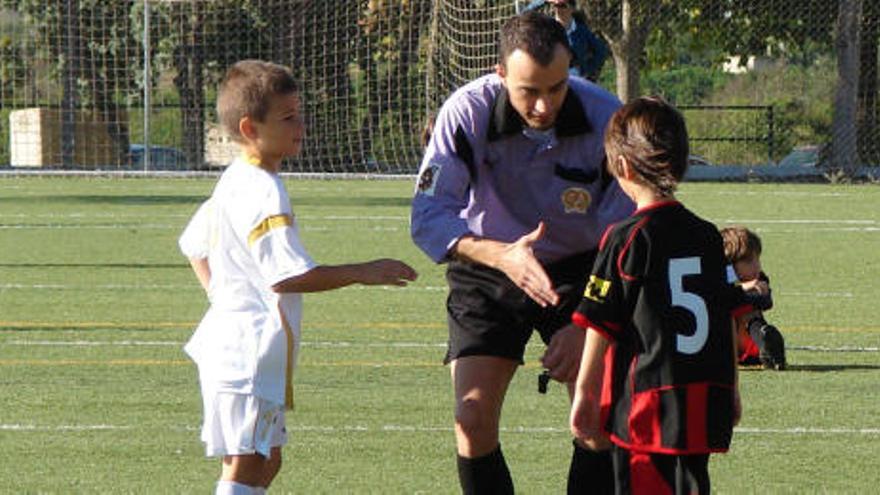 Un árbitro saluda a dos pequeños capitanes.