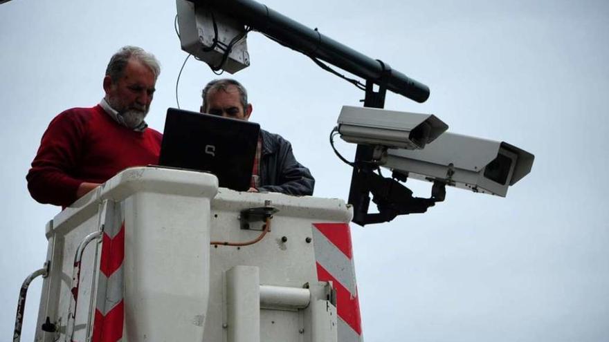 Un par de operarios durante la instalación de una de las cámaras foto-rojo en un semáforo de Vilagarcía. // Iñaki Abella