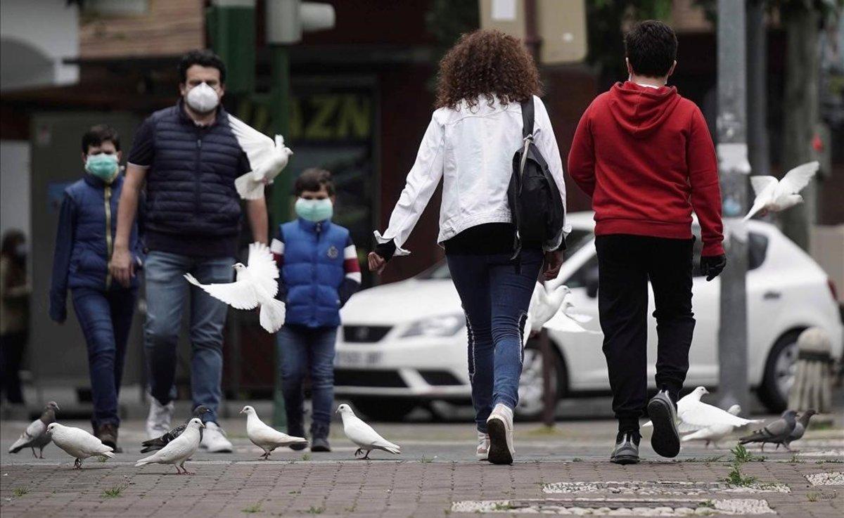 Una familia, protegida con mascarillas, pasea por una calle.