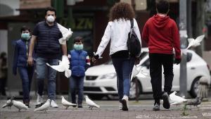 Una familia, protegida con mascarillas, pasea por una calle.