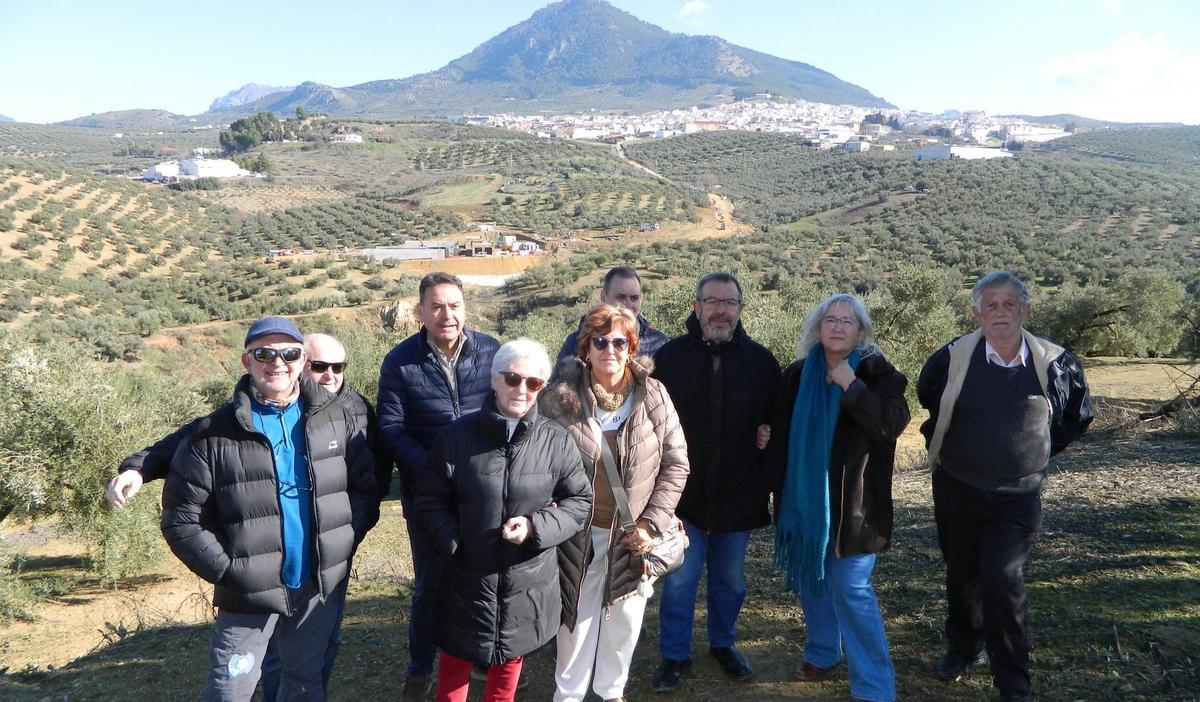 Vecinos y empresarios que recogen firmas contra la ubicación de la depuradora de Rute,cuyas obras se ven al fondo.