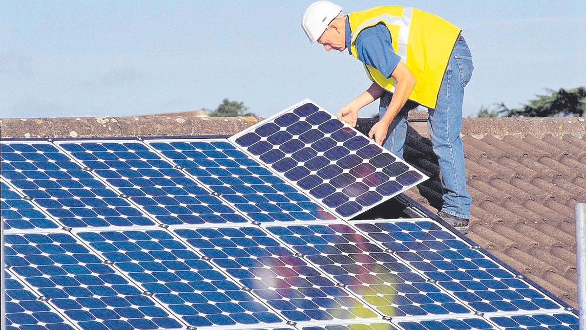 Un operario instala paneles solares que contribuyen al ahorro en el consumo de energía en el inmueble.