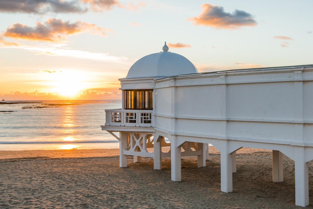 Romántica puesta de sol en la playa de Cádiz con famoso muelle