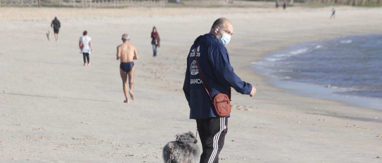 Vecinos paseando ayer por la playa de Rodeira y, al fondo, una persona haciendo deporte tras darse un chapuzón.