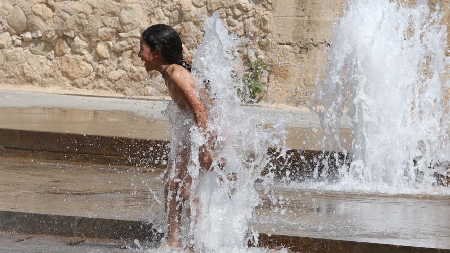 Una niña se refresca en una fuente de Elche para mitigar las altas temperaturas