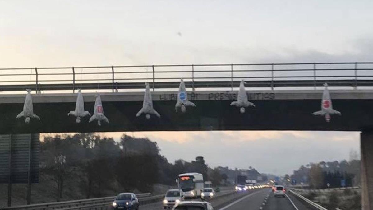 Bultos con forma humana y con los logotipos de Ciutadans, PSC y PPC, colgados de un puente de la C-17.