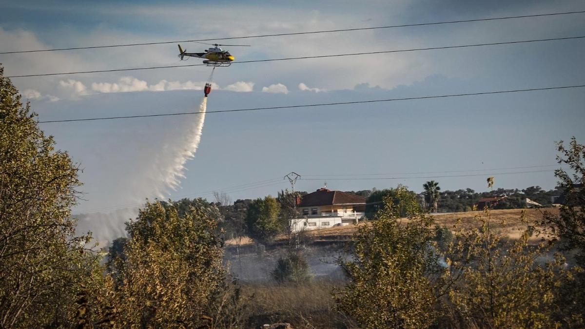 El helicóptero lanza agua sobre el fuego en la carretera de Sevilla.