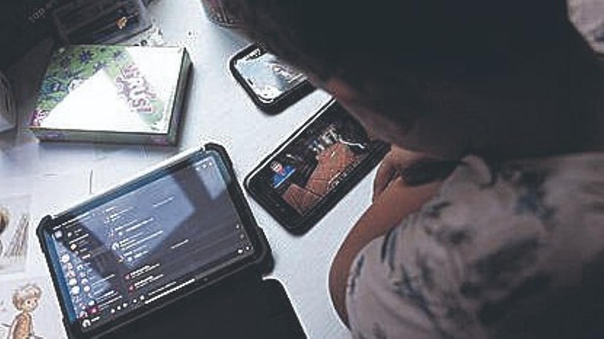 Un niño usa el teléfono móvil y una tablet, en Madrid.