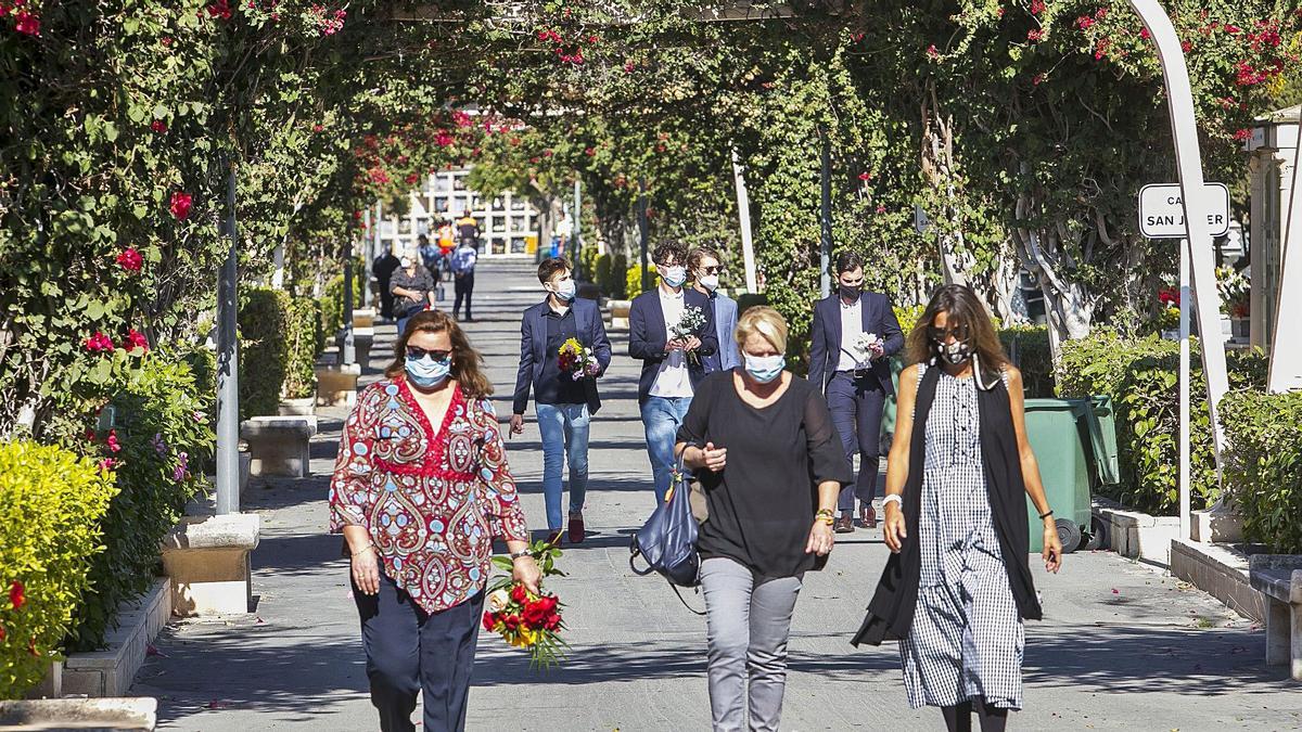 Familiares con ramos de flores para depositarlos en los mausoleos de sus seres queridos, ayer en el Cementerio de Alicante.