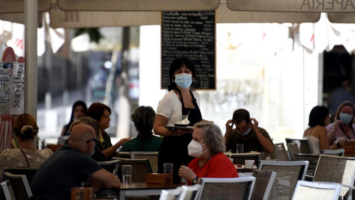 Una camarera atiende a unos clientes en una terraza de Madrid.