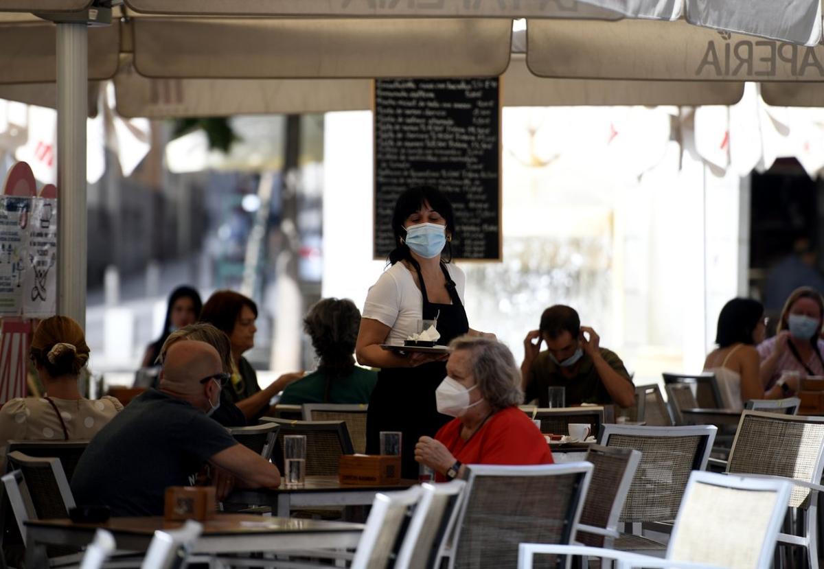 Una camarera atiende a unos clientes en una terraza de Madrid.