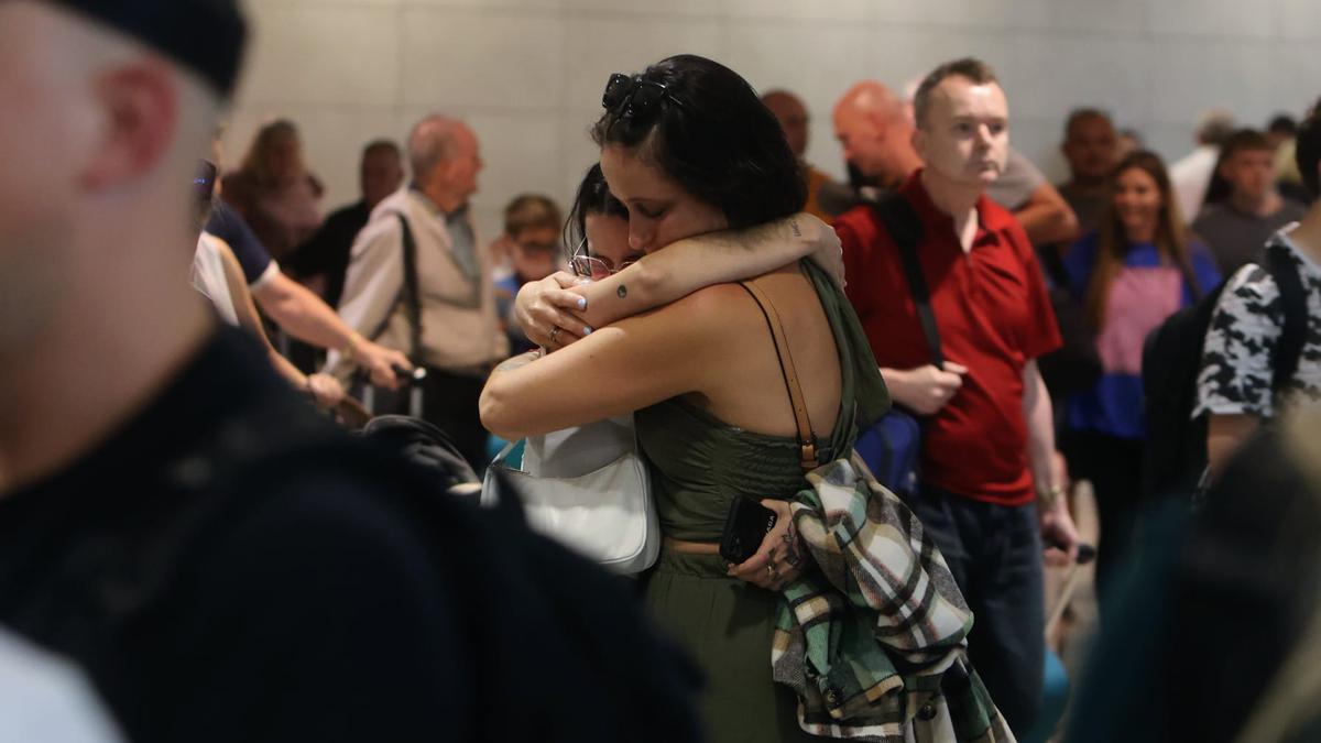 Dos personas se abrazan en la terminal.