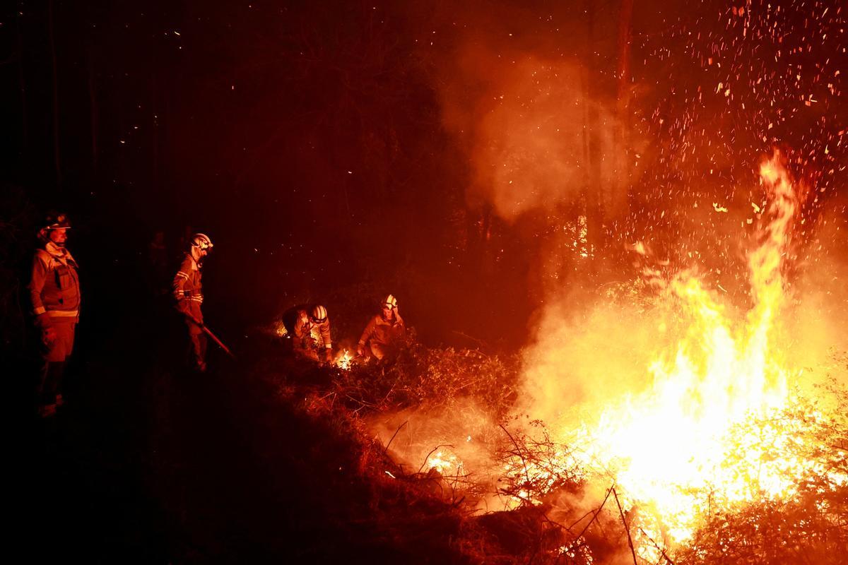 Un bombero gallego hace frente a las llamas en un bosque durante un brote de incendios forestales, en Piedrafita, Asturias