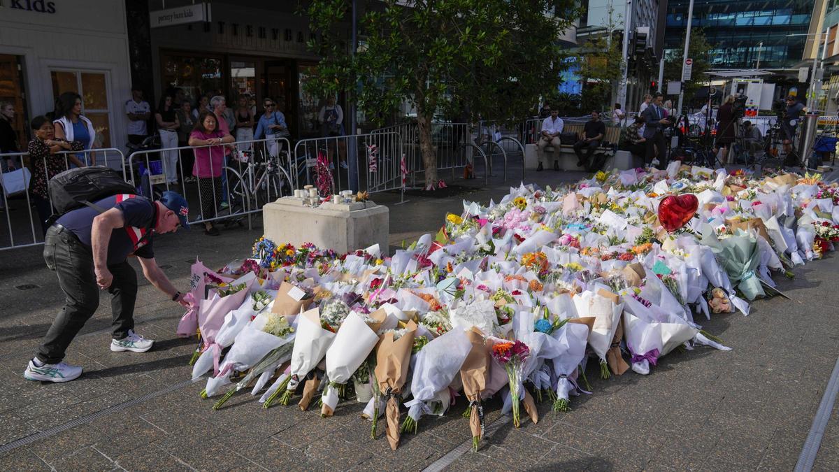 Un hombre coloca flores como homenaje cerca de la escena del crimen en Bondi Junction en Sydney.