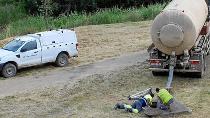 Operaris traient aigua del col·lector cap a un camió cisterna