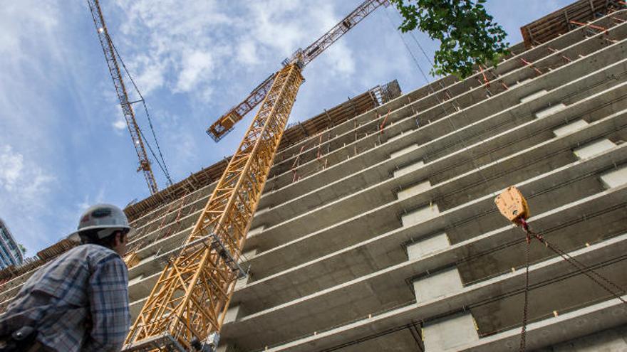 Un obrero contempla las grúas durante su jornada en la construcción de un gran edificio.