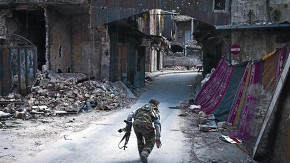 Un rebelde cruza una calle en Alepo intentando eludir a los francotiradores.