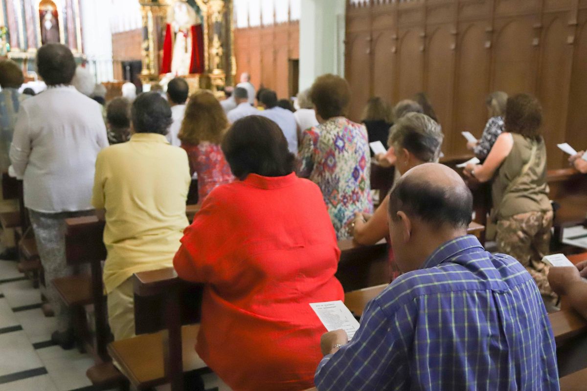 Los fieles leen la oración en las octavillas que se han repartido.