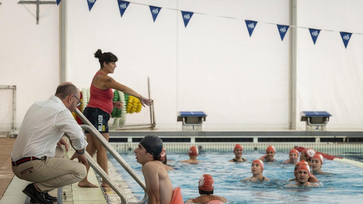 José Fernández charla al borde de la piscina con uno de los participantes del curso de instructor de gimnasia acuática.
