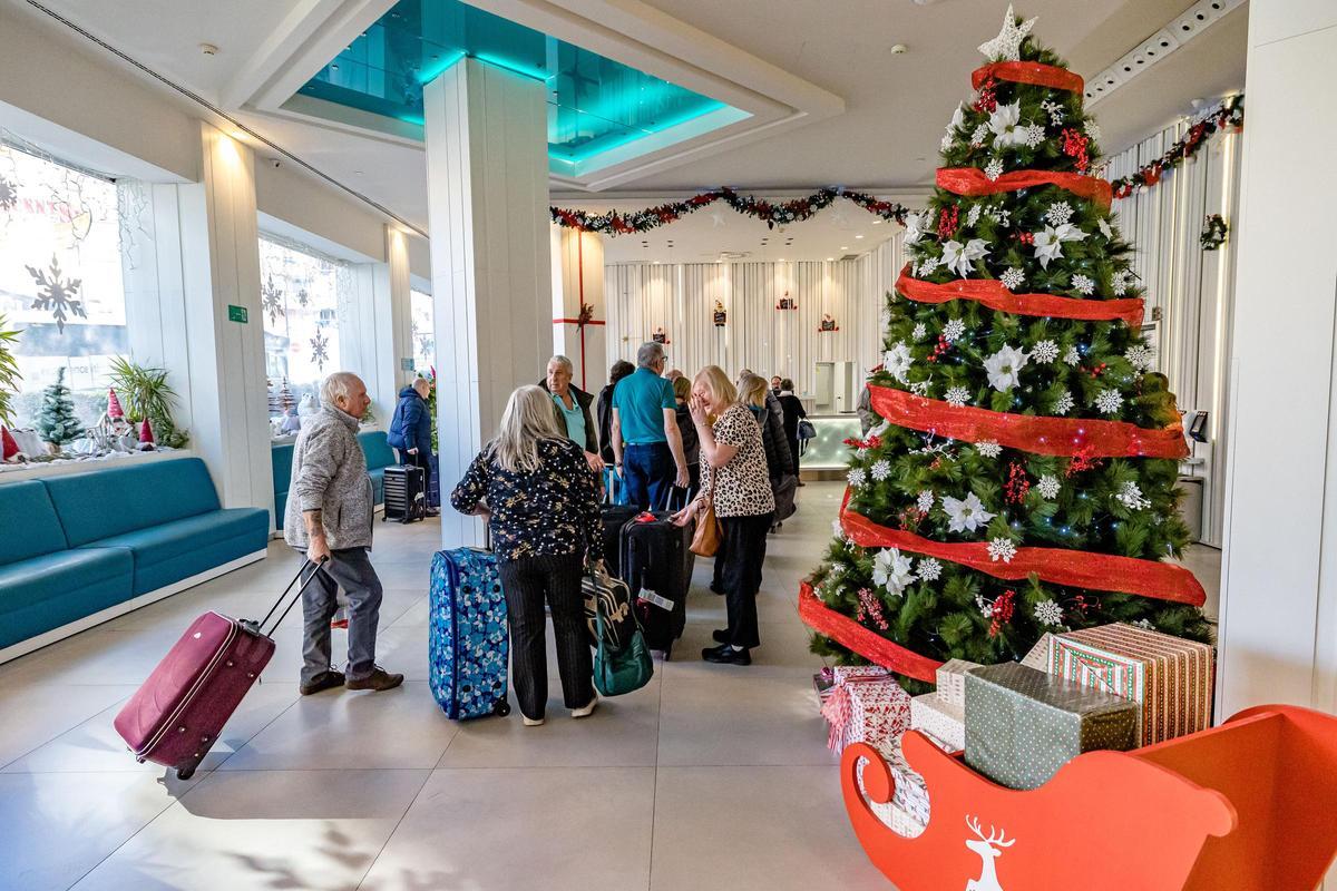 Turistas llegando a un hotel de Benidorm, con adornos para la Navidad.