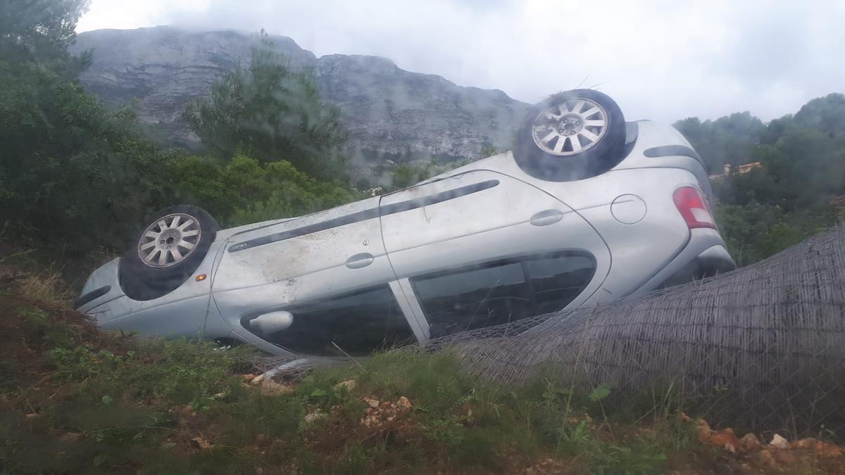 El coche, volcado y fuera de la calzada.