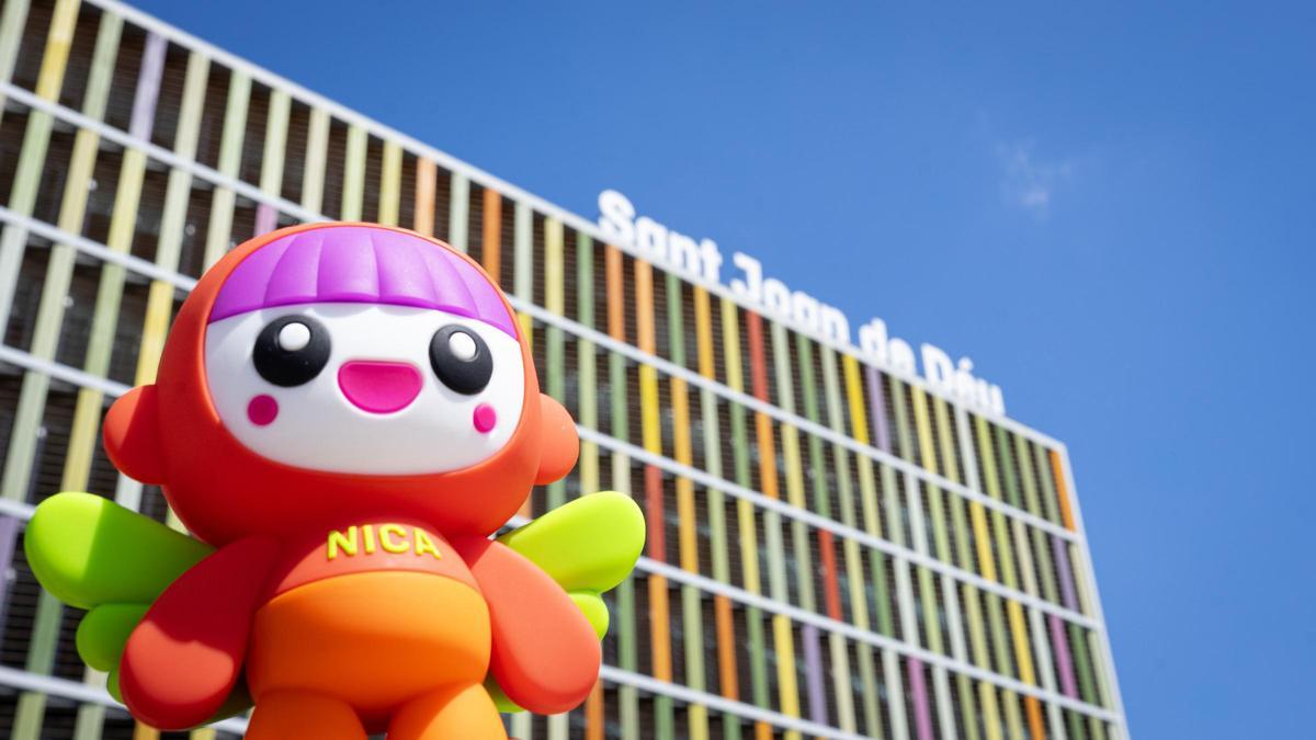 La muñeca Nica frente a la fachada de Sant Joan de Déu.