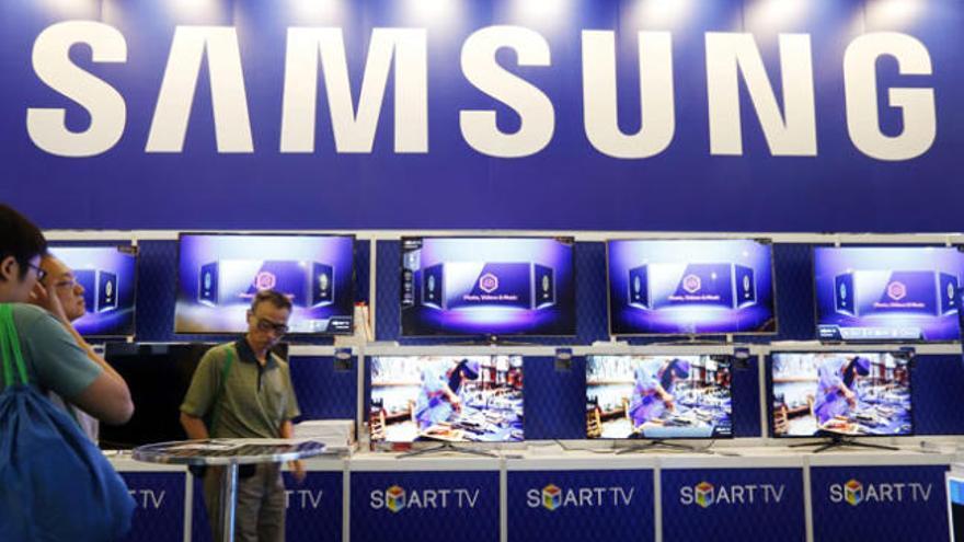 Varios visitantes pasan por delante de un puesto de Samsung