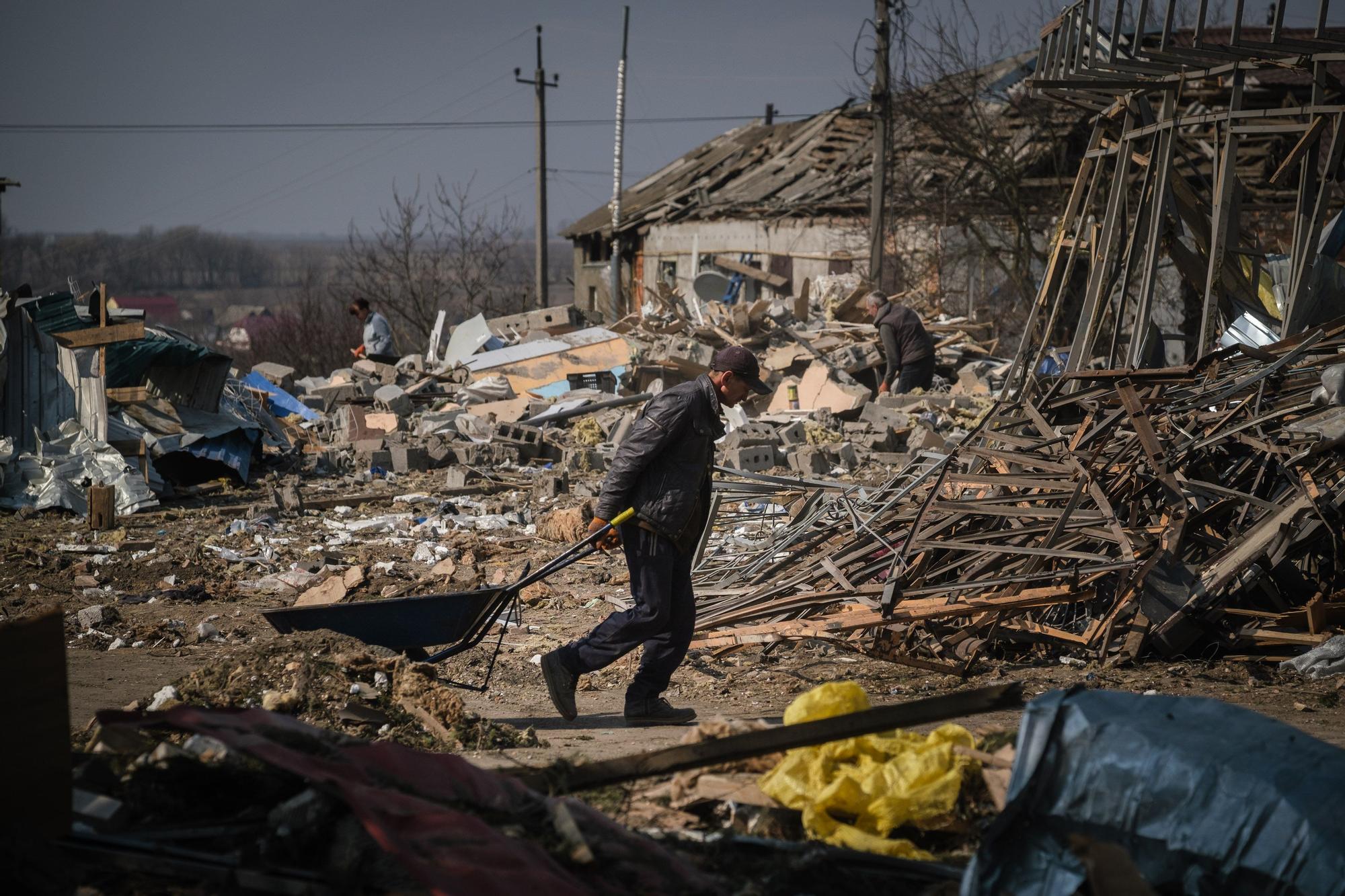 Un hombre arrastra una carretilla entre los escombros en un pueblo destruido a las afueras de Kiev
