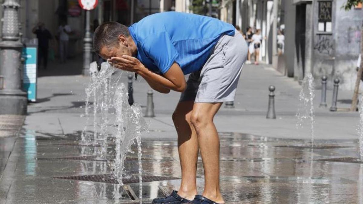 Un hombre se refresca en una fuente de Córdoba.