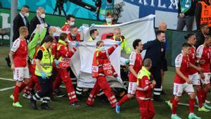 Players escort paramedics as Denmarks midfielder Christian Eriksen is evacuated from the pitch during the UEFA EURO 2020 Group B football match between Denmark and Finland at the Parken Stadium in Copenhagen on June 12, 2021. (Photo by WOLFGANG RATTAY / POOL / AFP)