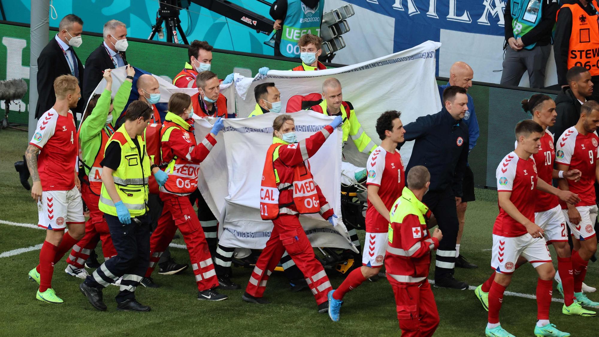 Players escort paramedics as Denmark's midfielder Christian Eriksen is evacuated from the pitch during the UEFA EURO 2020 Group B football match between Denmark and Finland at the Parken Stadium in Copenhagen on June 12, 2021. (Photo by WOLFGANG RATTAY / POOL / AFP)