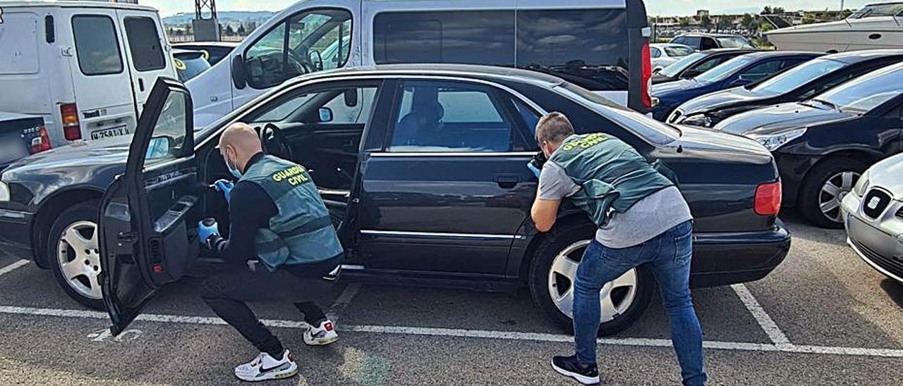 Dos agentes inspeccionan uno de los coches asaltados. |