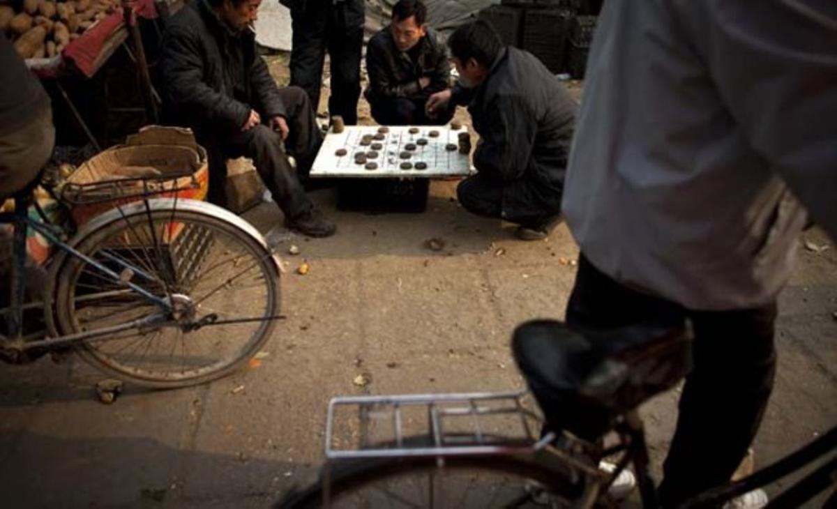 Venedors de verdures juguen a escacs xinesos en un mercat a Pequín (Xina).