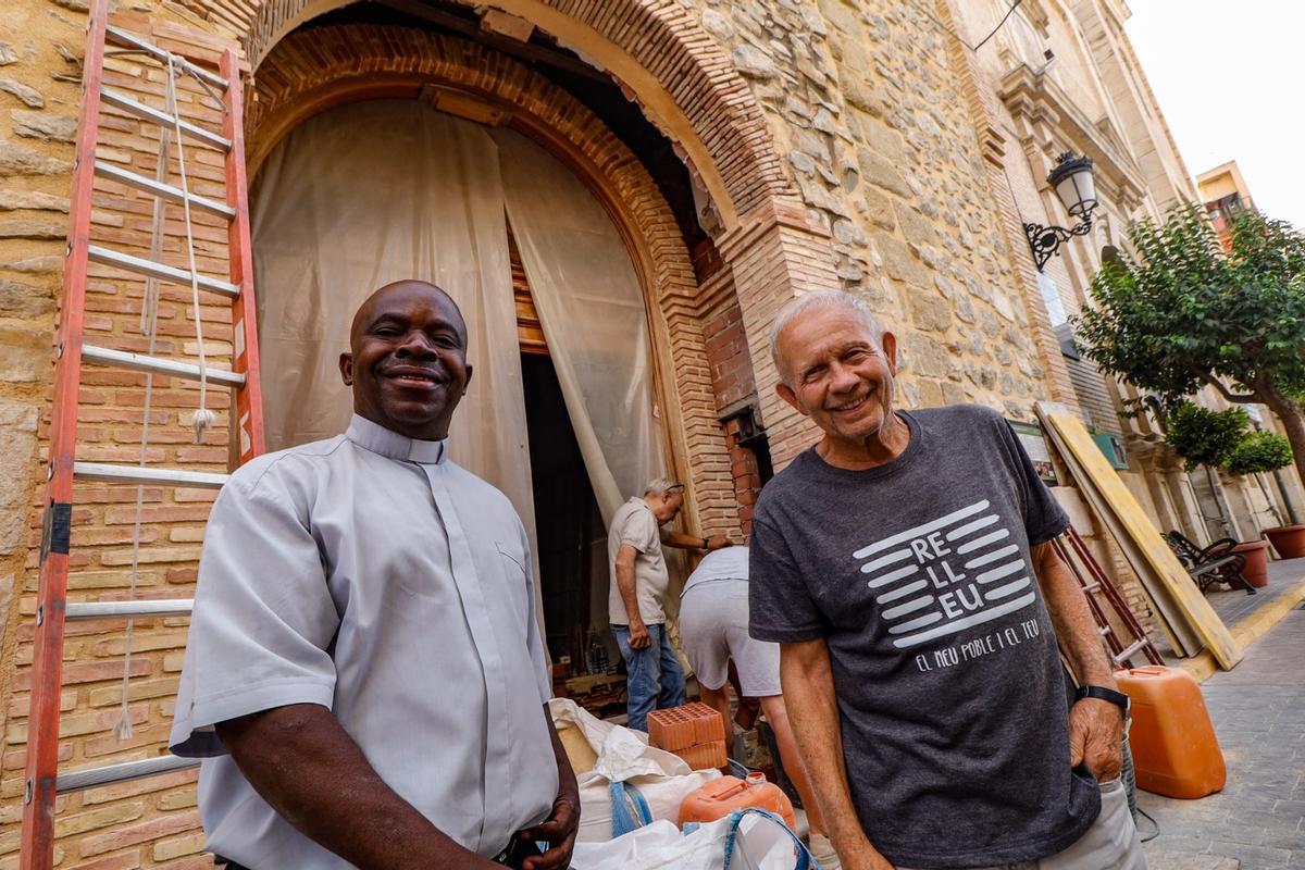 El padre Juan y su amigo Vicente frente a la puerta de la capilla que se está retranqueando