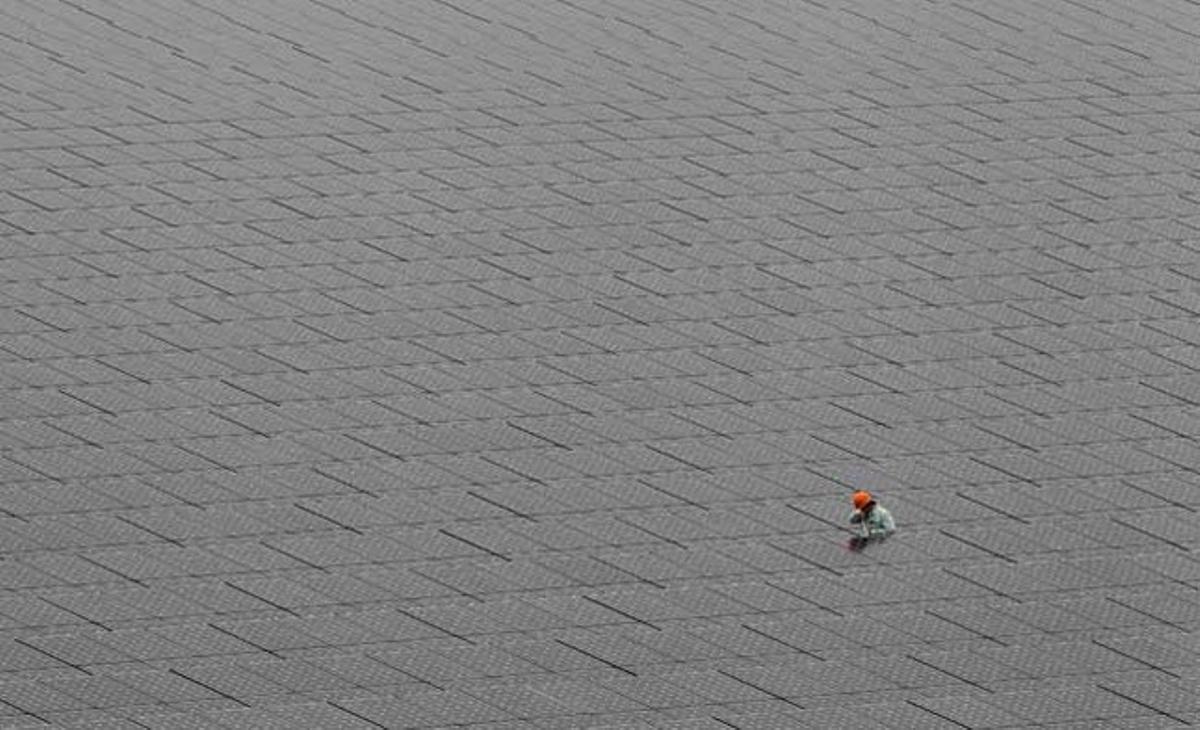 Un treballador camina enmig de panells solars en un camp d’energia solar a Kawasaki, a prop de Tòquio.