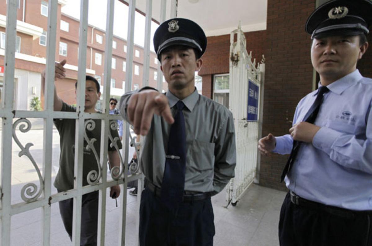 Dos guàrdies de seguretat impedeixen entrar als periodistes xinesos en un hospital, on està ingressat l’activista cec Chen Guangcheng.