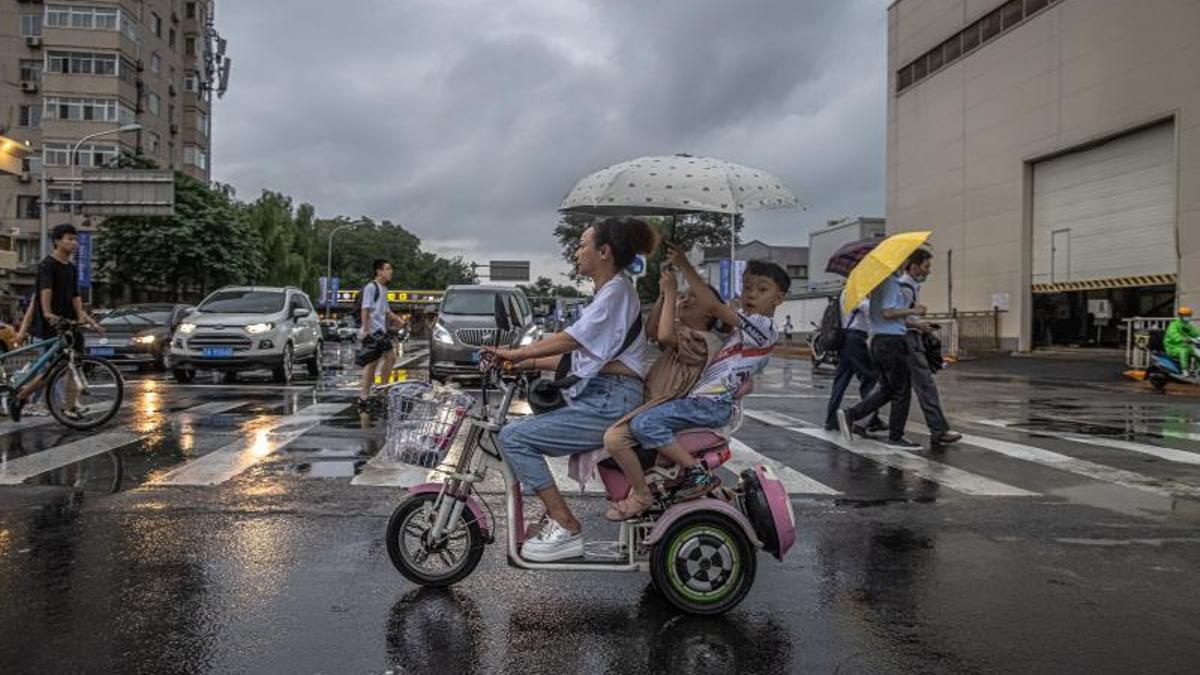 Una mujer y dos niños en moto durante un chaparrón en Pekín (China) este martes.