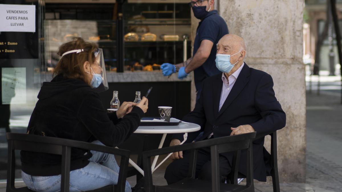 Dos vecinos de València disfrutan de una terraza con mascarilla.